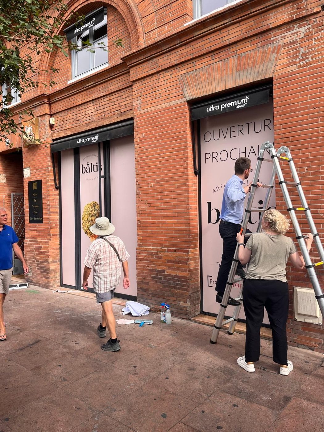 Pose du sticker d'ouverture sur la vitrine de Bältis à Toulouse